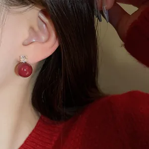 Detailed close-up of elegant red pearl drop earrings with zircon stud on model ear