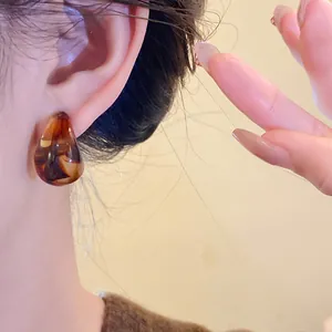 Detailed close-up of retro Maillard brown marbled acrylic stud earrings worn on ear