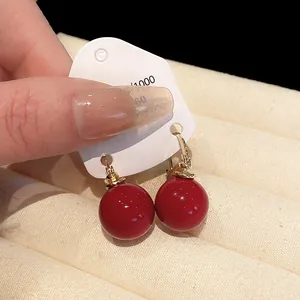 Elegant red pearl drop earrings with gold hooks shown on a white jewelry card.