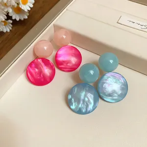 Macro view of resin geometric stud earrings with pearlescent texture in pink and blue.