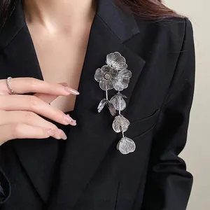 Elegante spilla a fiore traforato argento con nappe e strass su un blazer nero da donna
