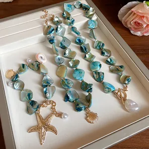 Detalle de collar de piedras azules con dijes dorados de estrella de mar y concha