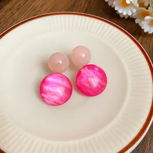 Macro view of retro pink resin geometric earrings with marbled fuchsia discs on saucer