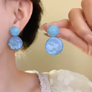 Blue resin double sphere stud earrings with marble texture on an Asian model