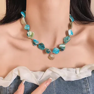 Detalle de un choker de piedra natural azul con un colgante de concha dorada en modelo