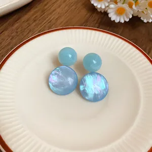 Detailed view of blue resin geometric stud earrings with shell-like shimmer on a plate