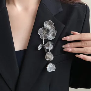 Primo piano di un'elegante spilla a fiore d'argento con strass e nappe su un blazer.