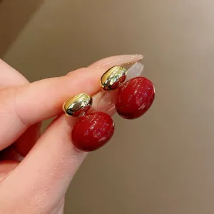 Close-up of vintage-style red and gold glossy bean stud earrings