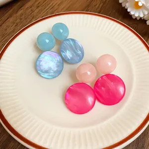 Detailed view of blue and pink resin geometric drop earrings placed on a vintage plate.