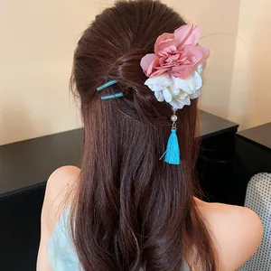Nahaufnahme eines chinesischen Blumen-Haarstabs mit blauer Quaste in einer Hochsteckfrisur.