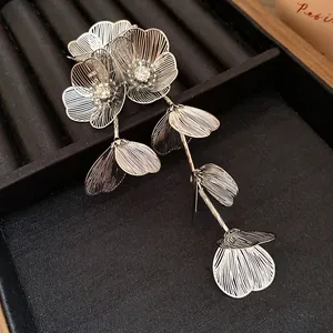 Dettaglio di elegante spilla a fiore traforato argento con strass e lunghe nappe