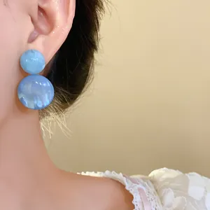Detailed close-up showing texture of elegant blue marble resin earrings on model