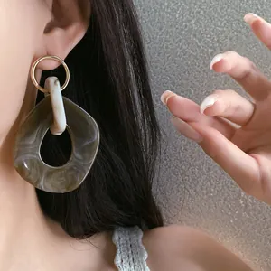 Primo piano di orecchini geometrici in resina marmorizzata su modella