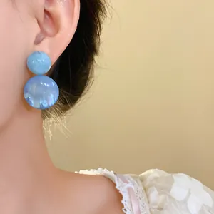 Detailed close-up view of elegant blue resin geometric drop earrings worn by a female model