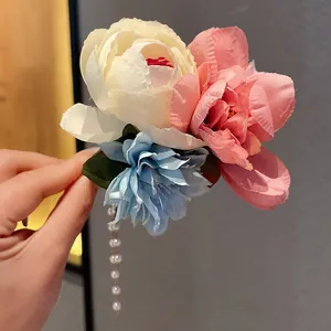 Nahaufnahme einer eleganten U-Haarnadel mit Stoffblumen und hängenden Perlenquasten.