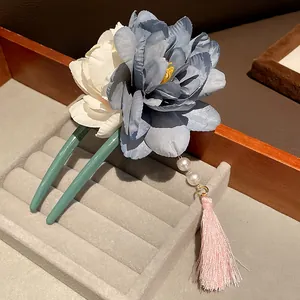 Detailaufnahme der eleganten blau-weißen Blumen-Haarnadel mit rosa Seidenquaste