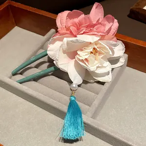 Detailansicht einer traditionellen U-förmigen Haarnadel mit Seidenblumen und Quaste.