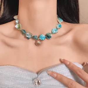 Primer plano detallado de una gargantilla de piedra natural azul con colgante de concha