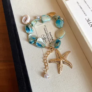 Primer plano de collar de piedra natural con dijes de estrella de mar y conchas