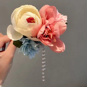 Detailansicht künstlicher Blumen und hängender Perlenquasten an einer Vintage-Haarnadel