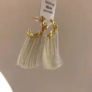 Primo piano di orecchini a nappa a forma di C plissettati in oro e argento
