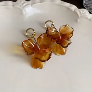 Retro amber flower resin earrings with golden hoops displayed on an elegant white tray