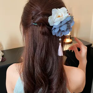 Nahaufnahme einer eleganten zweifarbigen Blumen-Haarnadel mit Perlenquaste in braunem Haar