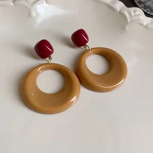 Close-up of retro Maillard brown and red resin hoop earrings on a white plate.