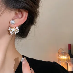 Eleganti orecchini a fiore con perle bianche e oro indossati da una modella in dettaglio