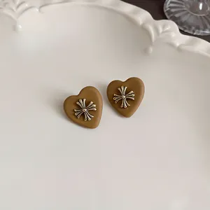 Detailed view of matte coffee brown heart-shaped earrings featuring a metallic cross