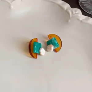 Close-up view of retro geometric resin earrings with marble texture on a white plate