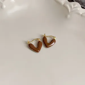 Detailed close-up of glossy Maillard brown heart-shaped earrings with elegant gold hooks