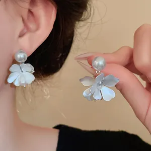 Close-up detail of vintage style white flower petal earrings with large round pearls