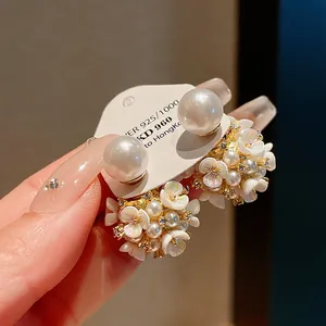 Primo piano di eleganti orecchini a fiore con perle e dettagli dorati rifiniti