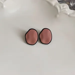 Close-up of matte brown irregular organic shape stud earrings with black trim