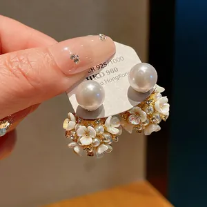 Primo piano ravvicinato di eleganti orecchini a lobo con fiori, perle e cristalli