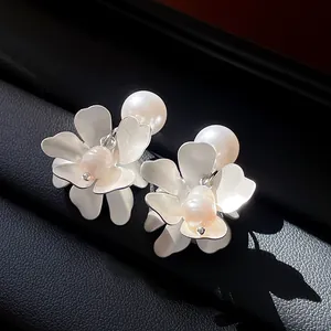 Close-up detail of vintage silver flower earrings with elegant freshwater pearls.