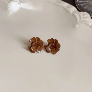 Detailed close-up of coffee brown flower stud earrings on a cream vintage ceramic plate
