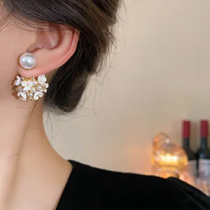 Primo piano di orecchini a fiore con perle indossati sull'orecchio, sfondo caldo