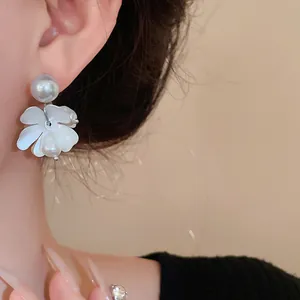 Close-up of elegant white flower earrings with freshwater pearls on model's ear