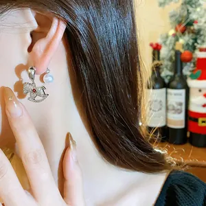 Close-up detail of rocking horse pearl stud earrings worn by model in festive setting