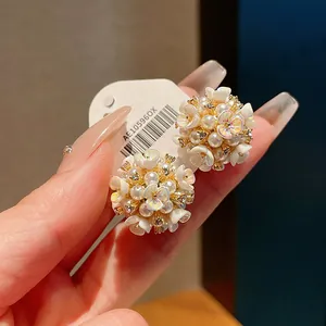 Dettaglio ravvicinato di orecchini vintage a fiore con perle, cristalli e oro