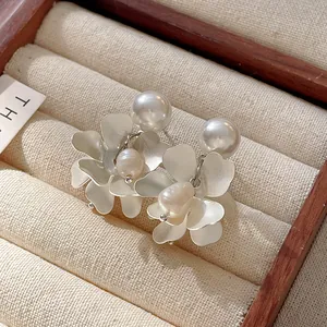 Detailed macro view of French vintage flower earrings with freshwater pearls and silver needles.