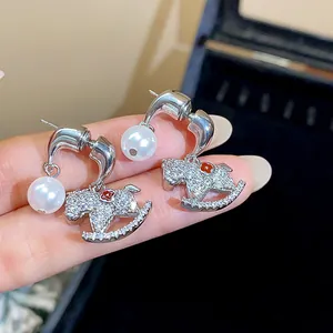 Close-up of 18K gold-plated silver needle rocking horse earrings with pearls and crystals.