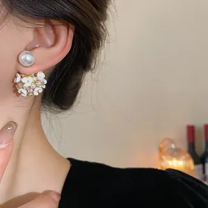 Dettaglio di eleganti orecchini a perno con fiori bianchi e perle indossati sull'orecchio