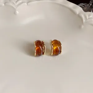 Close-up detail of amber brown resin earrings with elegant gold-toned metal accents