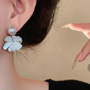Detailed close-up of French retro flower earrings with elegant white pearls and silver needles