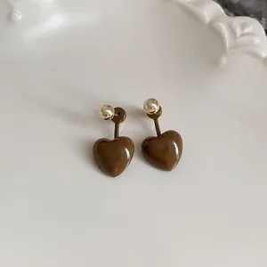 Detailed view of coffee brown heart-shaped stud earrings with gold accents