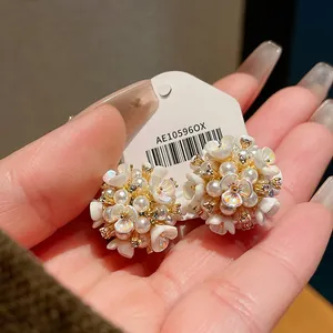 Dettaglio di orecchini a lobo a forma di fiore vintage con perle e accenti dorati in oro