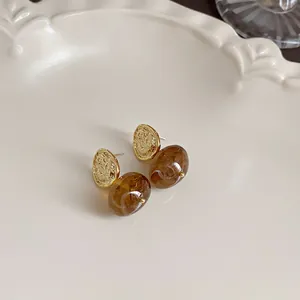 Detailed shot of elegant vintage brown amber-style earrings with gold textured studs